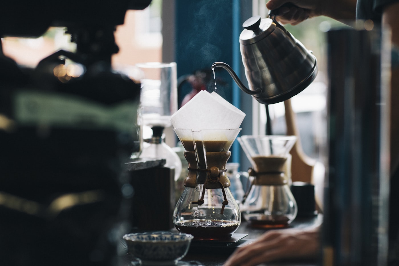 A barista pouring water over a coffee filter by hand